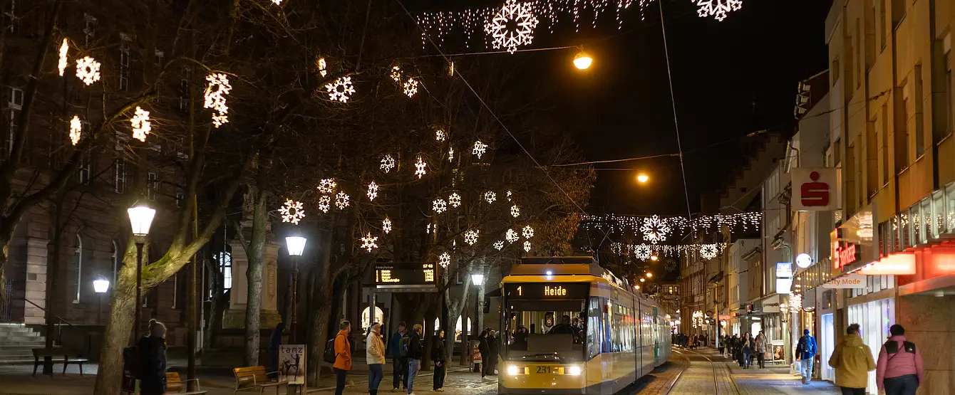 Eine Tram der Linie 1 fährt durch das weihnachtlich beleuchtete Durlach. 