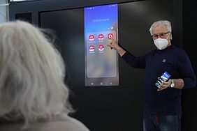 Smartphone mit Apps wird von einem älteren Herren gezeigt. 