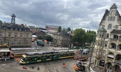 Eine Trambahn der Verkehrsbetriebe Karlsruhe passiert bei einer Testfahrt das erneuerte Gleisviereck an der Tullastraße. Im Hintergrund sind das Schlachthof-Areal und das Schloss Gottesaue zu sehen.