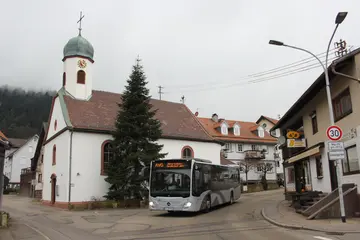 Der Bus der Albtal-Verkehrs-Gesellschaft auf seiner Abschiedsfahrt in der Ortsmitte von Bernbach. Im Hintergrund ist die Kirche zu sehen. 