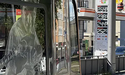 Das Foto zeigt die Preis-Säule an einer Tankstelle. Am linken Bildrand ist eine Straßenbahn zu sehen.