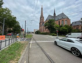 Ein weißes Auto steht an einer roten Ampel am neuen Fußgängerüberweg in der Durlacher Allee. Im Hintergrund ist die Bernharduskirche zu sehen.
