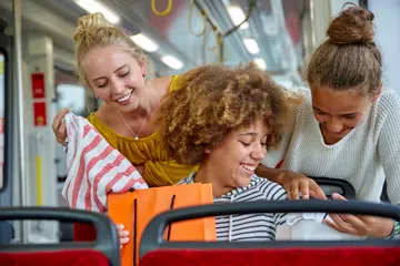 Drei Schüler*innen sitzen in einer Trambahn.