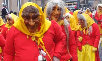 Eine maskierte Fastnachtgruppe in rot-gelbem Häs läuft beim Umzug in Durlach durch die Pfinztalstraße