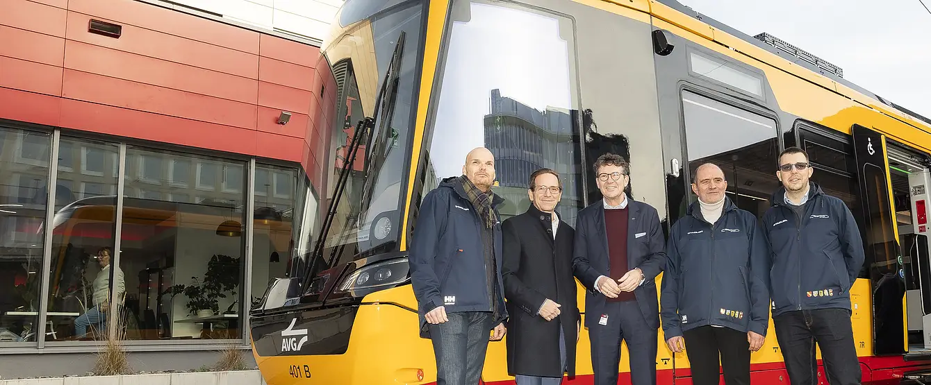 Vier Männer stehen vor dem gelb-rot lackierten VDV-TramTrain.