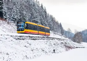 Eine AVG-Stadtbahn fährt durch das verschneite Albtal.