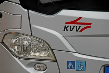 Scheinwerfer eines silbernen Bus mit dem KVV-Logo.