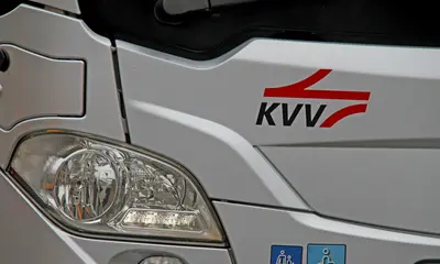 Scheinwerfer eines silbernen Bus mit dem KVV-Logo.