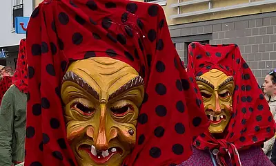 Mitglieder der Grötzinger Fastnachtsgruppe "Hottscheck"-hexen mit Häs und hölzernen Masken bei einem Fastnachtsumzug