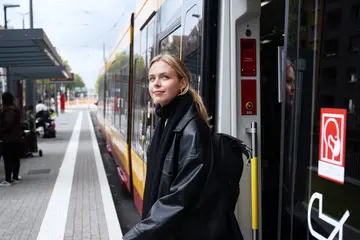 Eien Frau steigt an einer Haltestelle in Karlsruhe aus einer Bahn aus.