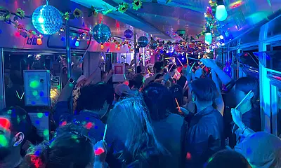 Partyatmosphäre mit bunten Lichtern in einer Bahn mit Menschen.