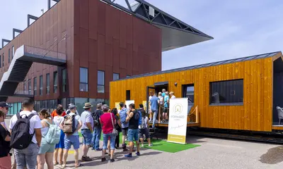 Besucher warten bei der Messe New Housing 2024 auf den Eintritt in ein Tiny House.