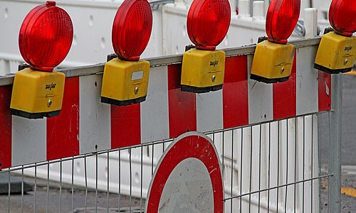 Rot-Weiße Absperrbarke mit roten Warnleuchten und einem Verkehrsschild, das "Durchfahrt verboten" signalisiert