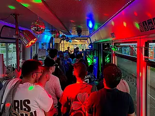 Innenansicht der Karaoke-Bahn mit Menschen und bunten Partylichtern.