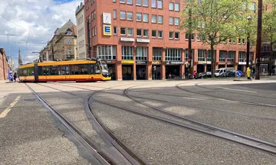 Der Kreuzungsbereich von Kaiserstraße und Fritz-Erler-Straße. Vorne ist ein Gleisbogen zu sehen, hinten passiert eine VBK-Trambahn die Kreuzung.
