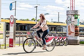 Eine Frau auf einem nextbike-Fahrrad. Im Hintergrund sieht man eine gelbe Straßenbahn