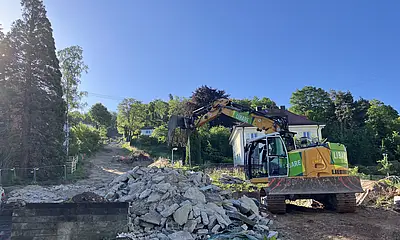 Das Foto zeigt des Rückbau der alten Talstation der Turmbergbahn. Ein gelber Bagger schaufelt Betonreste zur Seite.
