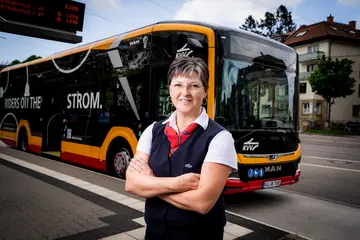 Eine Busfahrerin der VBK steht vor dem modernen Elektrobus.
