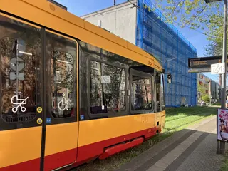 Eine Bahn der Tramlinie 2 passiert den Streckenabschnitt bei der Haltestelle Gritznerstraße. Im Hintergrund ist ein Gebäude mit einem Baugerüst zu sehen.