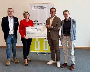 Das Foto zeigt die Übergabe des symbolischen Förderschecks durch Landes-Wirtschaftsministerin Dr. Nicole Hoffmeister-Kraut an die AVG.  