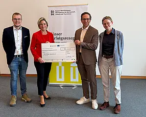Das Foto zeigt die Übergabe des symbolischen Förderschecks durch Landes-Wirtschaftsministerin Dr. Nicole Hoffmeister-Kraut an die AVG.  