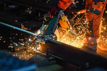 Das Symbolbild zeigt Bauarbeiten am Glas während der Nacht. Funken sprühen. 