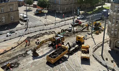 Blick auf die Baustelle an der Tullastraße. Es sind gelbe Bagger und Lastwagen zu sehen.