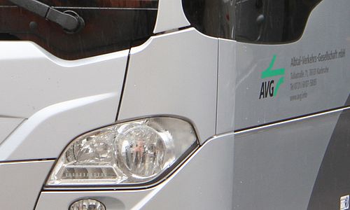 Frontpartie eines silberfarbenen Busses mit AVG-Logo neben dem Radkasten