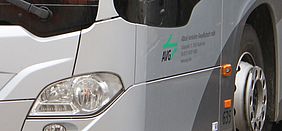 Frontpartie eines silberfarbenen Busses mit AVG-Logo neben dem Radkasten
