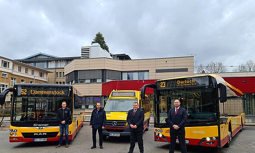 VBK-Mitarbeiter stehen vor drei neuen, gelb-roten Bussen. 