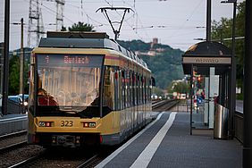 Eine Bahn der Tramlinie 1 an der Haltestelle Weinweg. im Hintergrund ist der Turmberg in Durlach zu sehen.