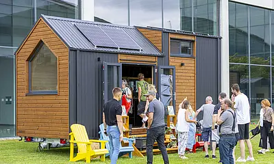 Besucher*innen des Festivals "New Housing" besichtigen ein ausgestelltes Tiny House.