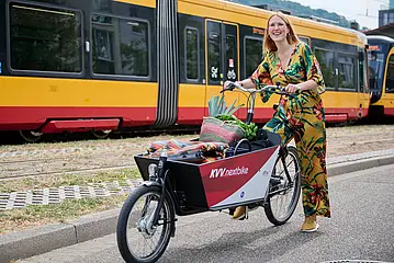 Eine Frau steht neben einem Lastenfahrrad.