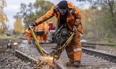 Ein Mann führt am Oberbau eines Bahngleises Schweißarbeiten durch