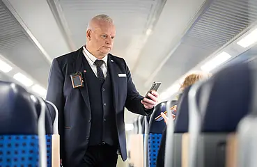 Ein Mitarbeiter des Prüfpersonals der Deutschen Bahn kontrolliert in einer Regionalbahn Fahrausweise. Dabei trägt er eine Bodycam.