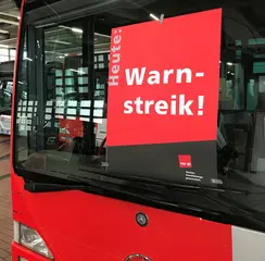 Ein Plakat zum Warnstreik von ver.di klebt an einer Busfensterscheibe. 