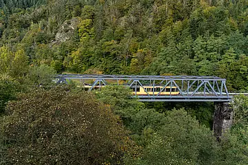 AVG-Stadtbahn fährt über Brücke im Schwarzwald.