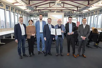 Gesellschafterbeitritt: Die Gesellschafter halten einen unterschriebenen Gesellschaftervertrag in die Kamera und lachen. 