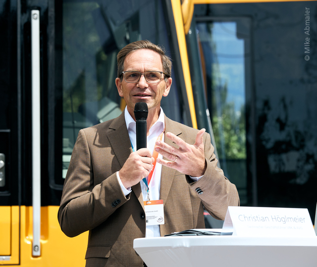Der technische Geschäftsführer Christian Höglmeier steht vor einer Stadtbahn und spricht in ein Mikrofon.